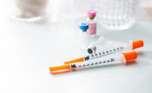 Medical syringes and medication vials on a white surface representing the testosterone injections vs gel comparison for men considering TRT delivery options