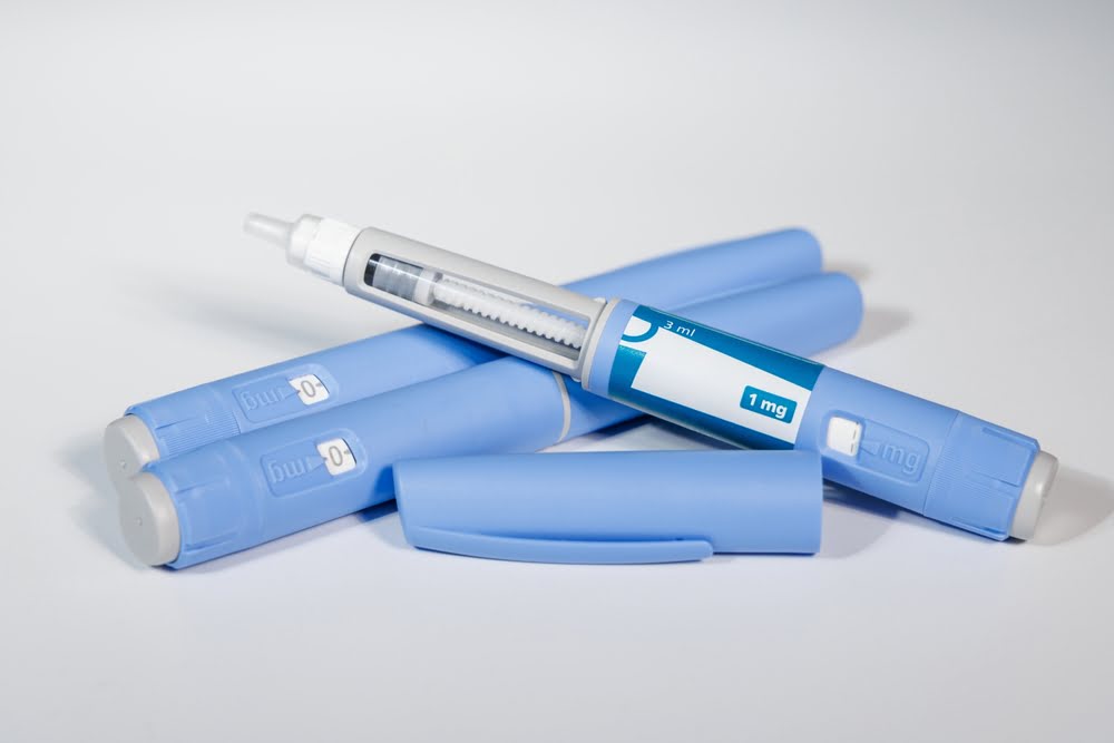 Multiple blue semaglutide injection pens stacked together on a white surface representing the growing availability and safety questions surrounding compounded semaglutide products