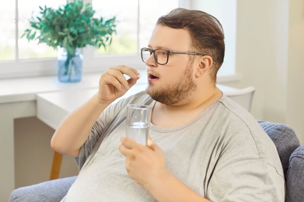 Overweight man taking prescription weight loss medication at home as part of a medical weight loss in Virginia telehealth program with Invite Wellness